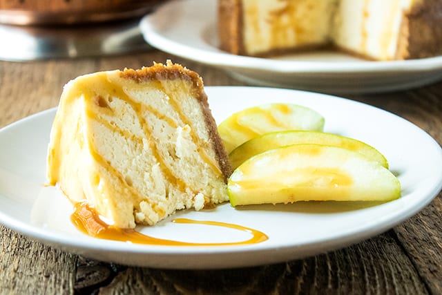 slice of instant pot cheesecake on a large white plate with apple slices