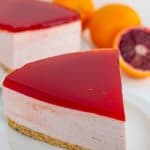 slice of blood orange cheesecake on a white plate with a sliced orange