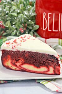 close up photo of cake on a white plate with a red cup behind it