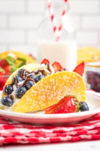 large cheesecake tacos on a white plate with a red and white checkered fabric under it